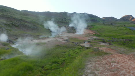 Birds-eye-flying-toward-geyser-geothermal-area-with-steaming-craters-in-Iceland.-Aerial-drone-view-of-spectacular-fumaroles