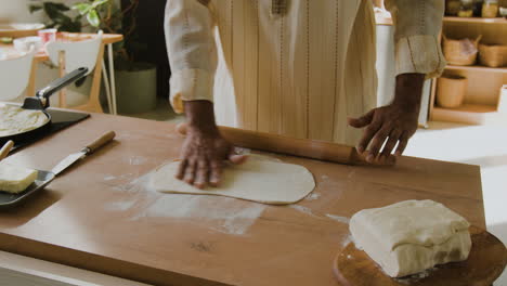 man rolling dough in kitchen