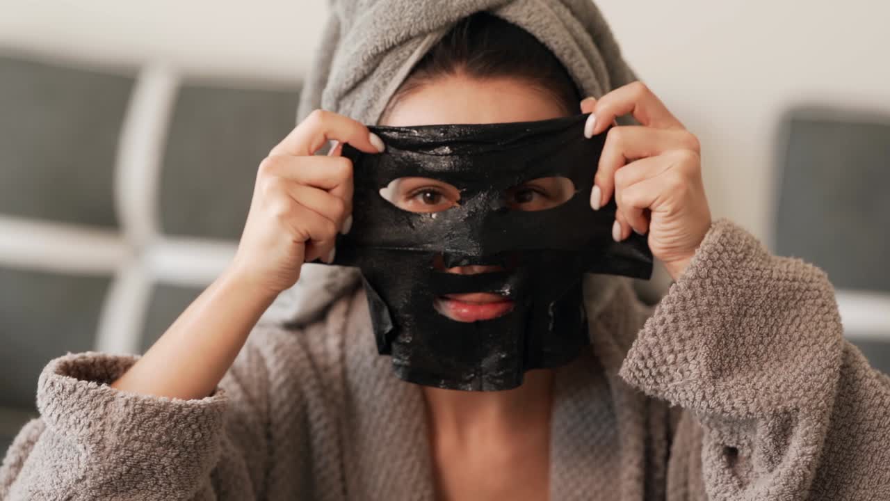 bella chica carismática lleva una máscara cosmética negra en la cara