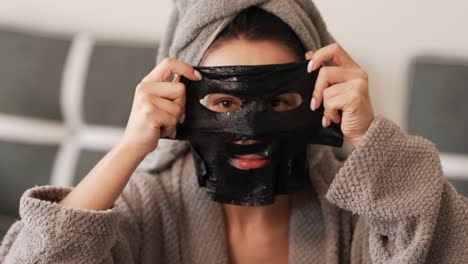 beautiful charismatic girl wears a black cosmetic mask on her face