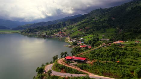 breathtaking aerial landscape of phewa lake with a village on the lakeside and mountain scenery, drone flying forward in pokhara, nepal