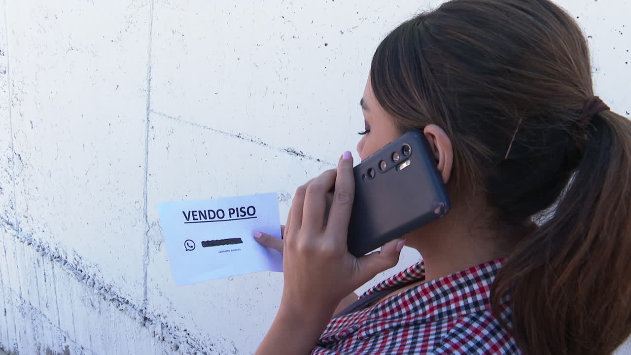 Woman Selling Property Using Phone and Poster