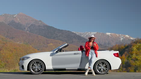 woman enjoying a scenic drive in a white convertible car with a view of autumn foliage and mountains