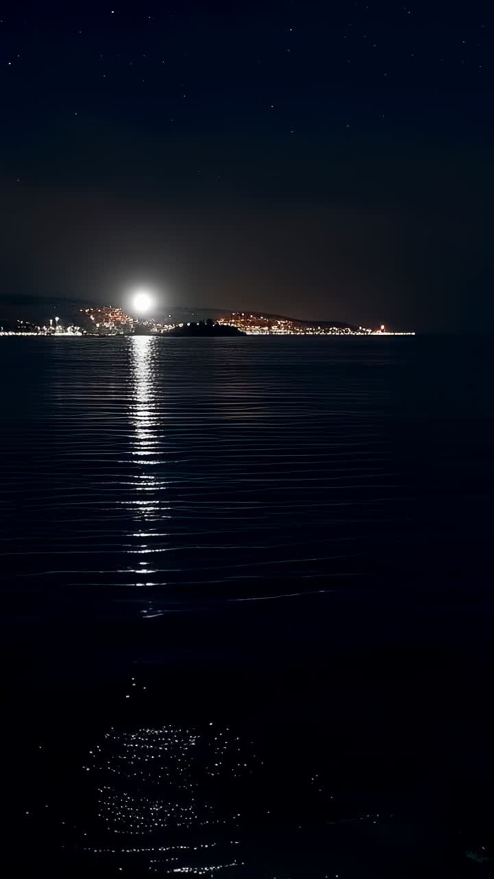 Video verticale: proietta una luce brillante all'orizzonte e crea una colonna di luce sul mare calmo, con increspature in movimento