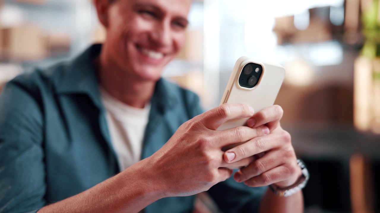 Smiling Man Using Smartphone in Warehouse Office