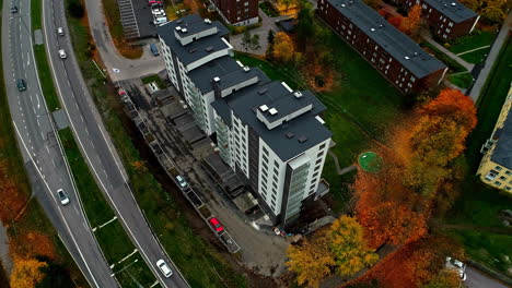 cars driving in the road along the high-rise apartment building in autumn