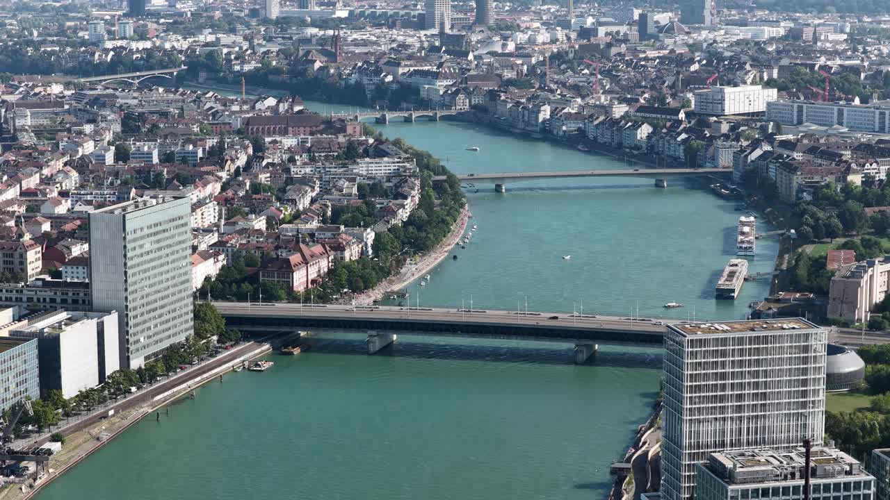 The Rhine River running through Basel, Switzerland, featuring the Dreirosenbrucke, railroad, and skyline infrastructure. aerial drone video