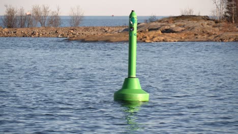 green navigation buoy floating in calm sea outside umeå harbour