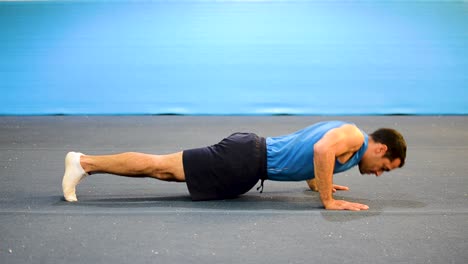 a guy doing a special kind of push up in a top-side-front view still shot inside a gymnastics gym