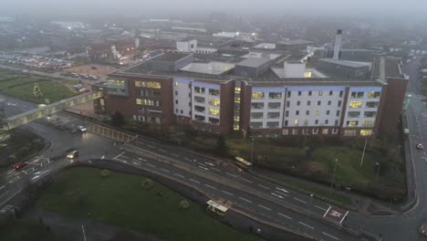 aerial view british nhs hospital on misty wet damp morning high to low descend