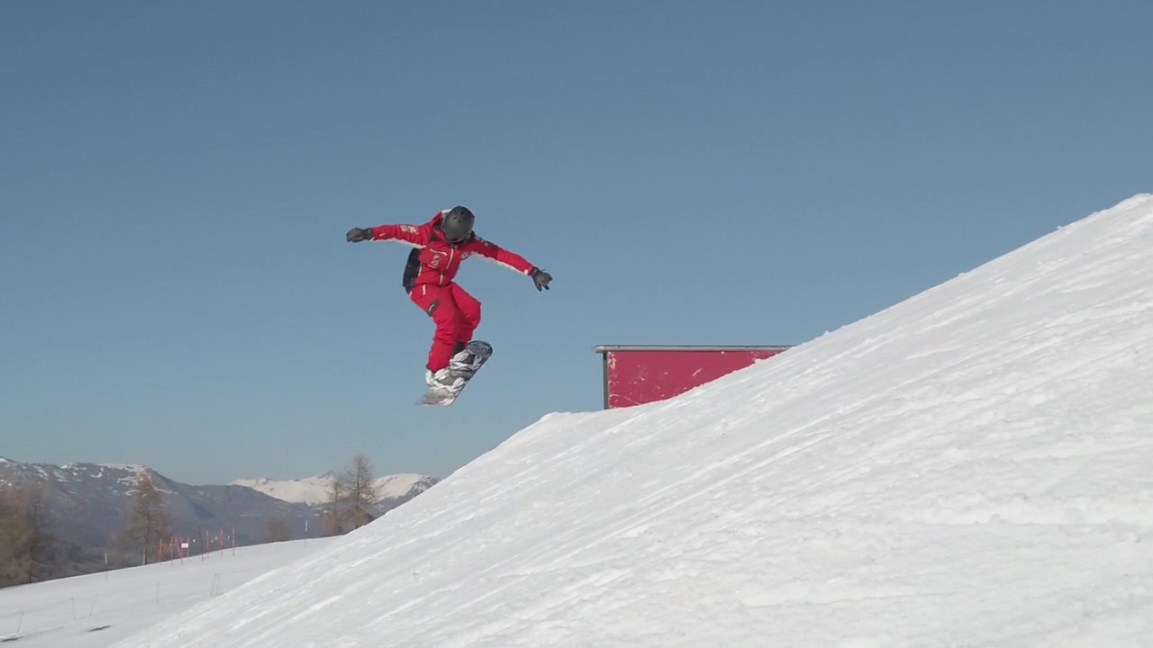Snøpark i Alpene med en skiinstruktør som hopper.