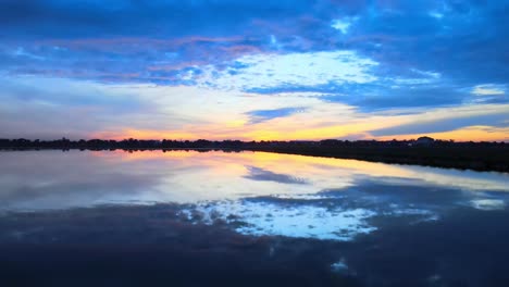 Antena:-Dron-Volando-A-Baja-Altura-Sobre-El-Agua-Que-Refleja-Perfectamente-Al-Impresionante-Amanecer