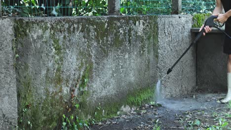 man using washer to wash concrete wall