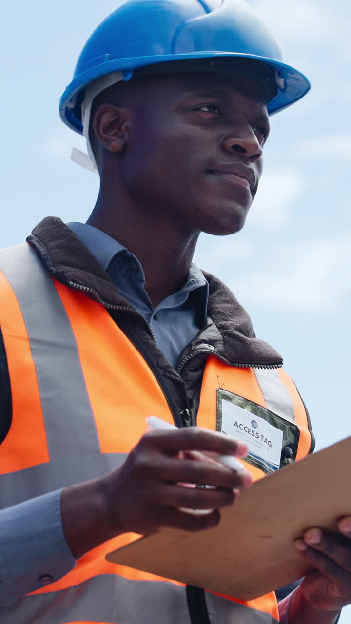 Focused Engineer in Hard Hat Writing on Clipboard Outdoors