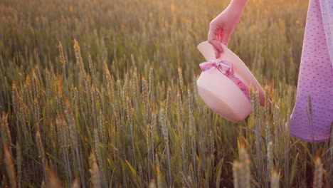 una mujer romántica camina por el campo verde lleva su sombrero de verano en la mano video 4k