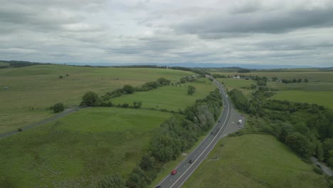 orbit of busy rural road a66 showing green countryside with reveal of hill great mell fell on cloudy summer day