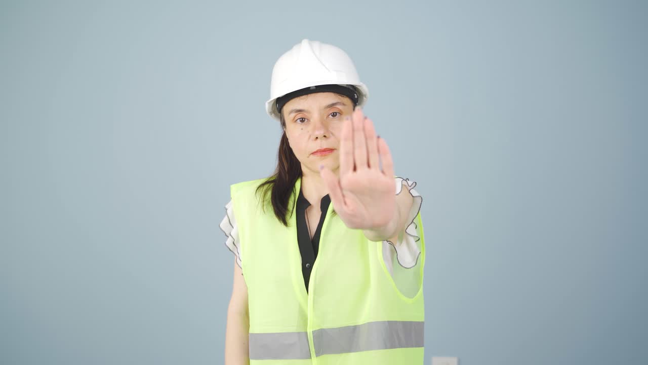 엔지니어는 카메라를 쳐다보고 정지 표지판을 만 ⁇ 니다.