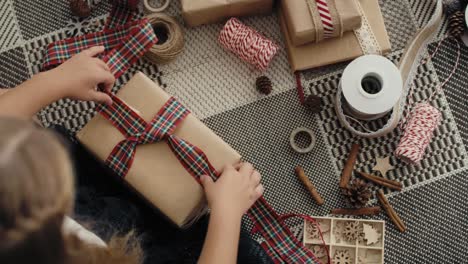 vista superior de una niña caucásica envolviendo regalos de navidad en el suelo.