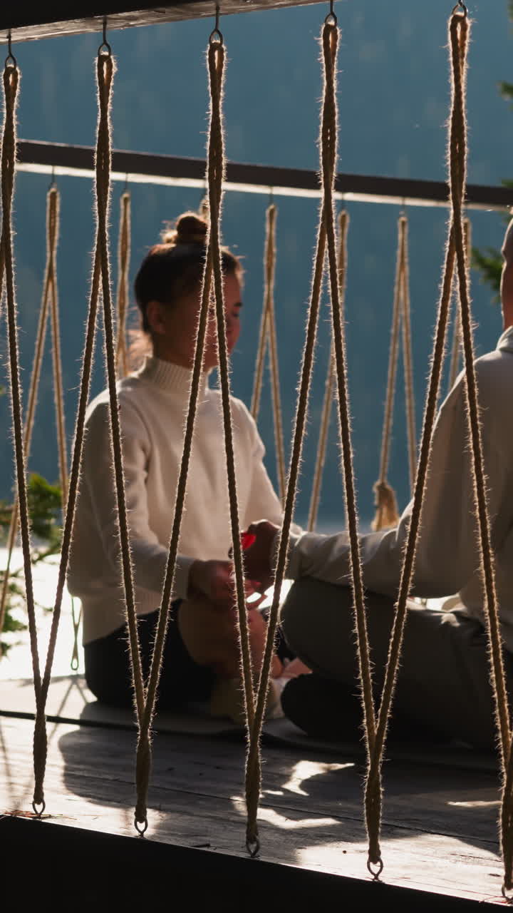 los socios comparten una sesión de meditación en la terraza sentados enfrente. un joven y una mujer realizan ejercicios de yoga que nutren la mente. un viaje holístico de auto-descubrimiento