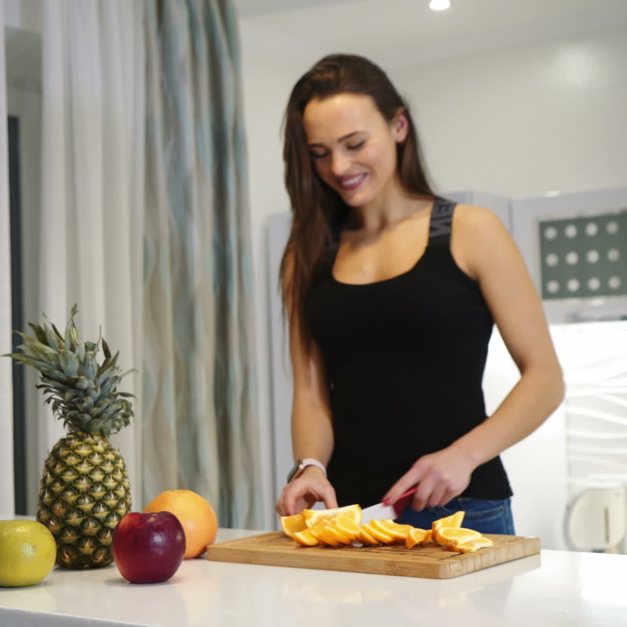 Sports woman is cutting an orange on a wooden board. Fresh fruits. Healthy lifestyle. Square video