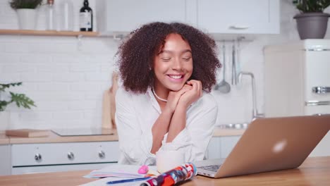 hispanic woman in love speaks and smiles when looking at laptop screen