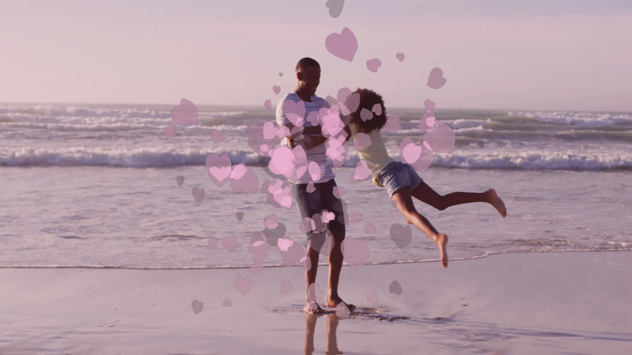 Father and daughter playing on beach with pink heart animation overlay