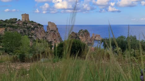 faraglioni or stacks of scopello in sicily and perched doria tower