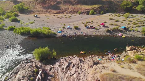 Kastanienbraunes-Schwimmloch-Am-Amerikanischen-Fluss-In-Kalifornien,-Umgeben-Von-Grünen-Bäumen-Und-Gefüllt-Mit-Menschen,-Die-Schwimmen-Und-Ihr-Sommerwochenende-Genießen---Rückwärts-Fliegende-Drohne