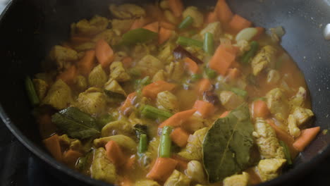 chicken and vegetable curry simmering in a pan