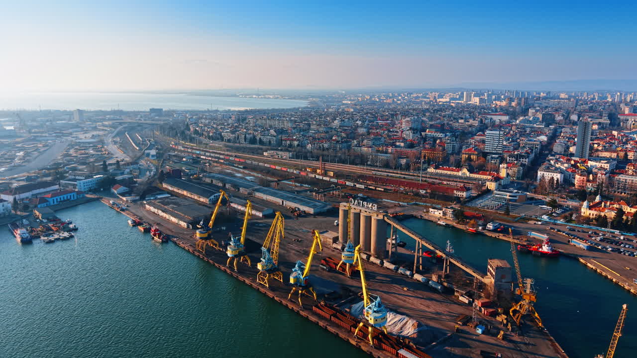High angle view of a port terminal and city skyline. Panorama of harbor quay with cranes, industrial buildings, and residential city area in the background