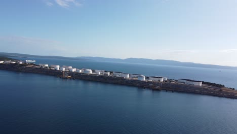 Drone-flying-alongside-an-industrial-island-in-the-mediterranean-against-the-wind-sideways-over-Krk