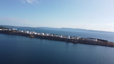 drone flying alongside an industrial island in the mediterranean against the wind sideways over krk