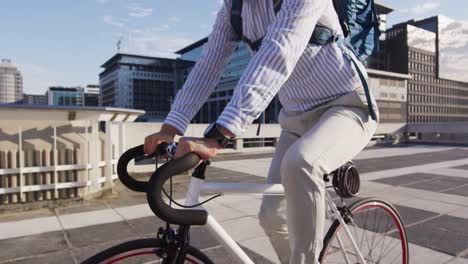 Asian-man-with-backpack-riding-bicycle-on-the-roof-of-corporate-park