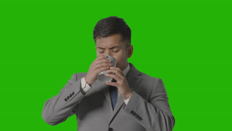 Studio-Shot-Of-Businessman-In-Suit-Holding-Cup-Of-Hot-Drink-Against-Green-Screen-1