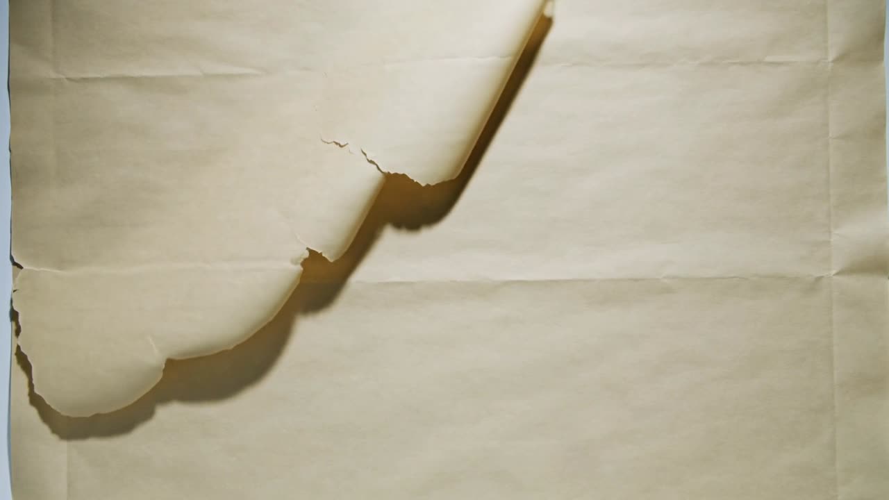 Angolo superiore sinistro di carta beige invecchiata che si scolla e si arriccia su un pannello chiaro, mostrando smerlature e pieghe.