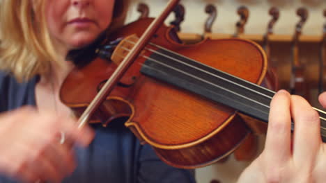 Close-Up-Of-Customer-Trying-Out-Violin-In-Music-Store