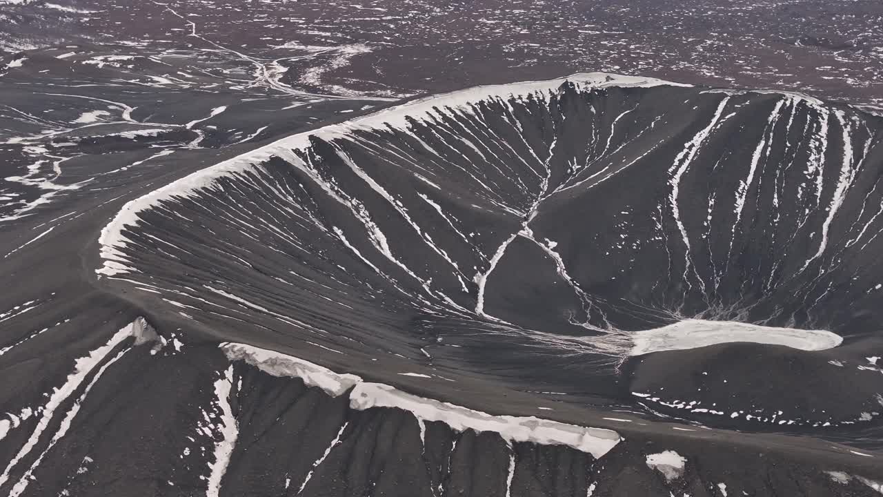 Aerial view of the massive Hverfjall crater near Mývatn, Iceland. Stark volcanic slopes etched with snow create a surreal, moon-like winter landscape of raw geological power.