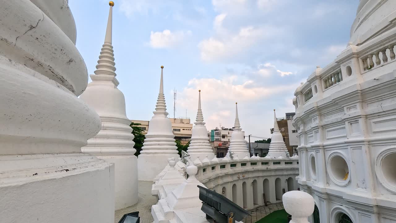 A tranquil scene of white stupas at Wat Prayurawongsawas in Bangkok, captured under soft daylight with a steady camera pan