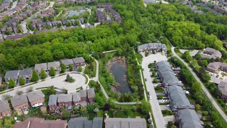 aerial view circling over a pond nestled in a green oakville neighborhood