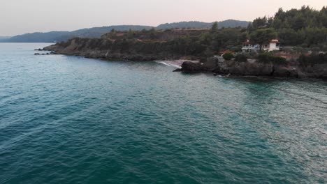 Drone-Aéreo-Sobre-La-Playa-Rocosa-Del-Mar-Egeo-Al-Atardecer-Aguas-Cristalinas