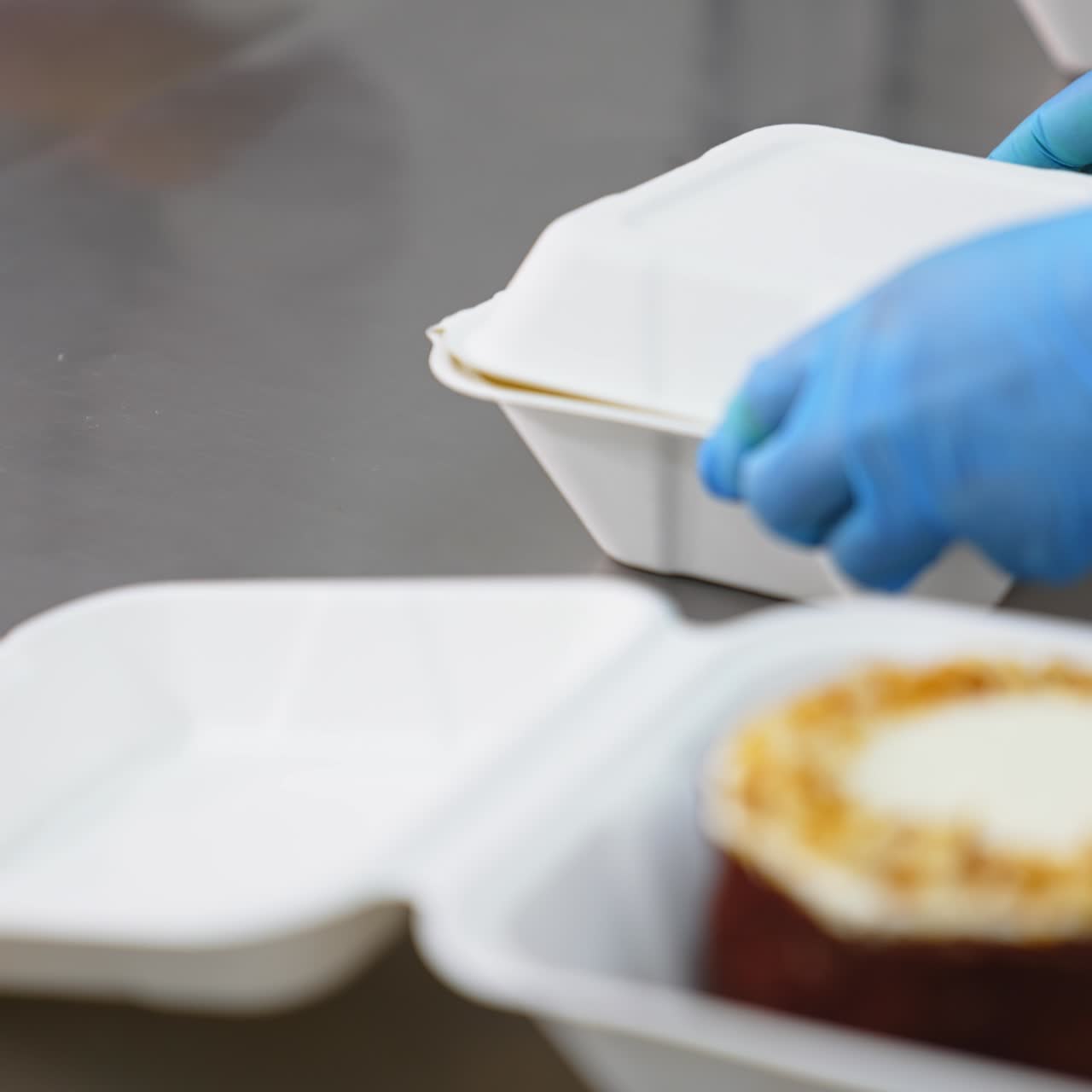 Packaging the ready-made sweet desserts in individual boxes. Hands in latex gloves put down the lids of packages. Close up
