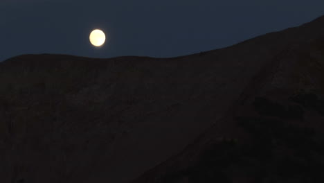 满月慢慢消失在科罗拉多洛基山脉的山脊后面 在夜晚的中间