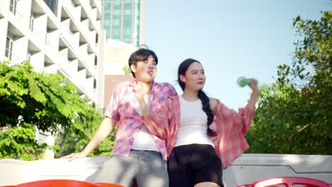 사랑에 빠진 젊은 아시아 커플이 오픈 에어 버스의 꼭대기에 춤을 추며 수도 메트로폴리탄 시를 돌아다니고 있다.