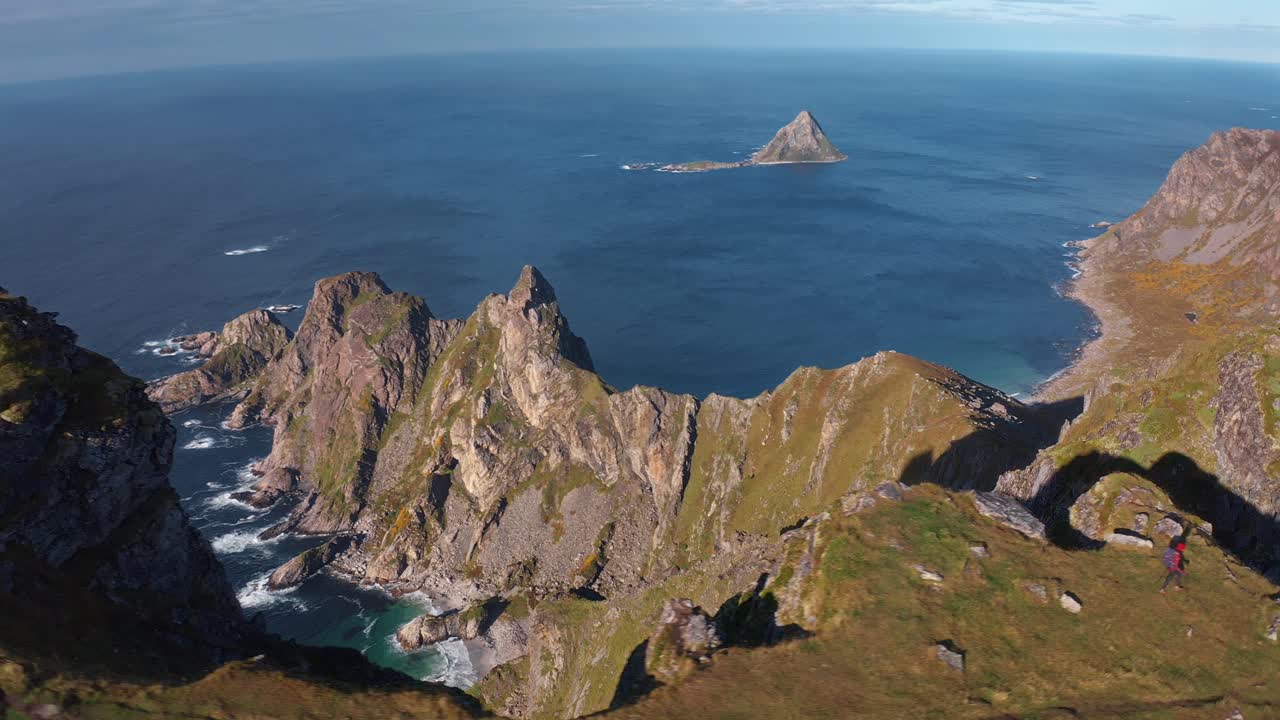 Majestic aerial view of Måtinden, with a lone tourist standing by rugged cliffs
