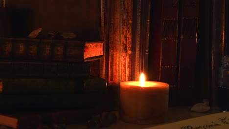 close up background of an ancient library, next to a frieplace, with old books, old paper, ink, stones, and a candle with flickering flame