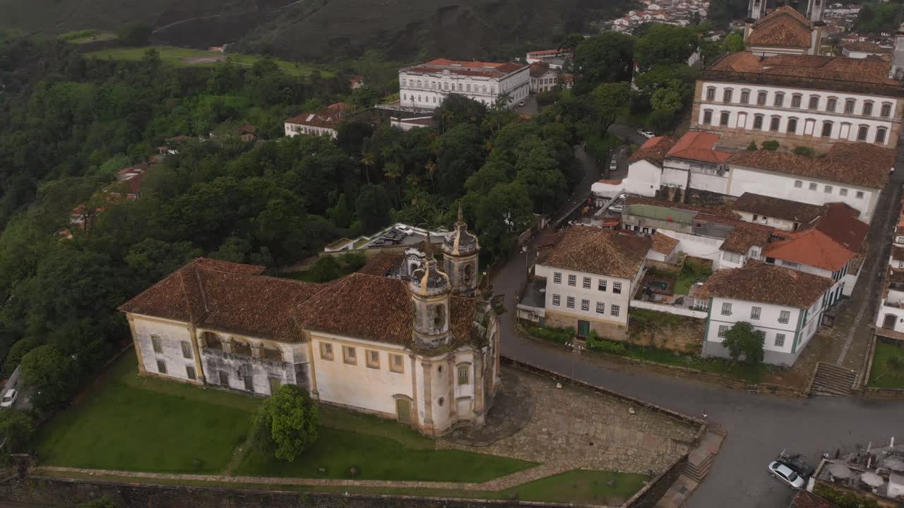 Aerial view of Saint Francis of Assisi church in Ouro Preto, Minas Gerais, Brazil, revealing the city centre with tourist fair and central Tiradentes square early in the morning with empty streets