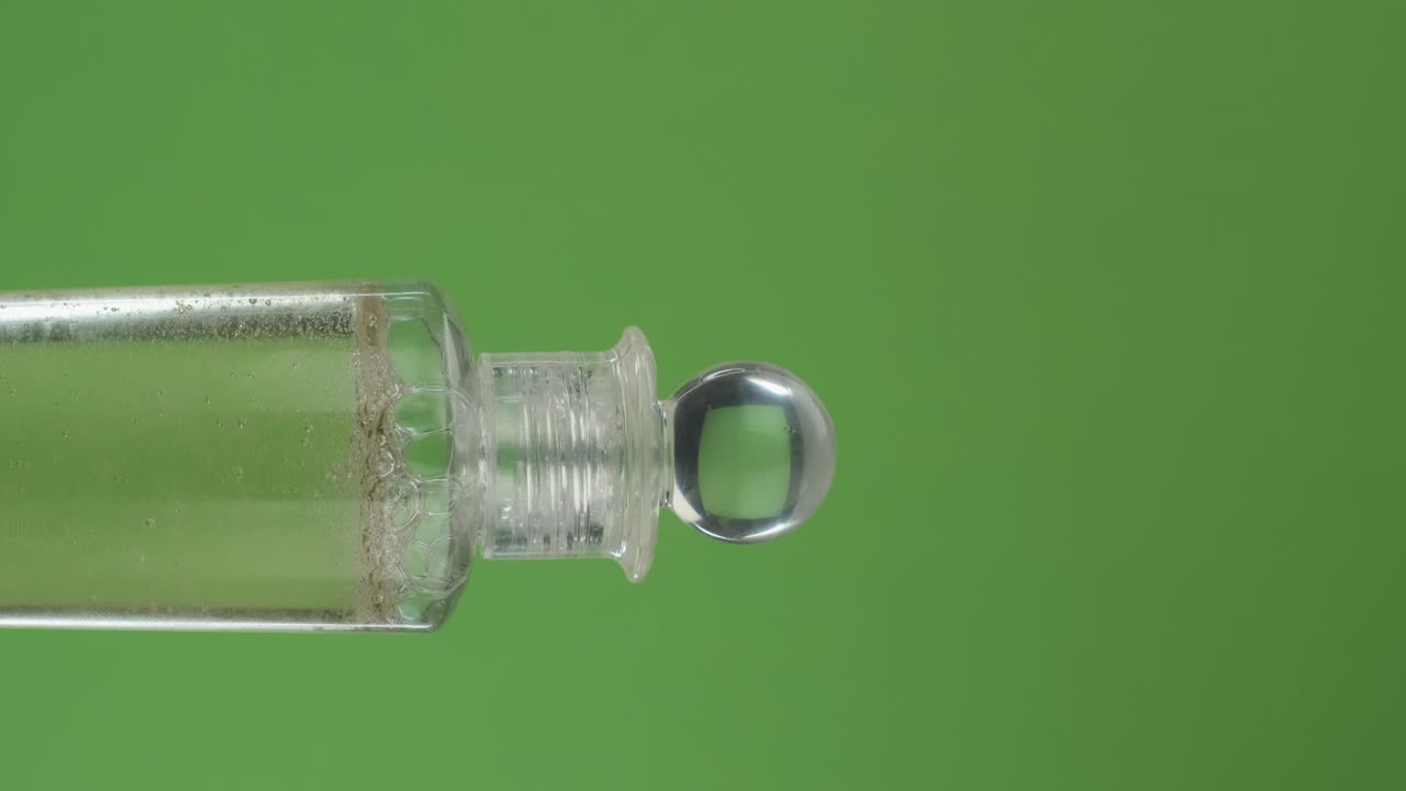 rotación horizontal de una botella de aceite cosmético, en una pantalla verde. primer plano.