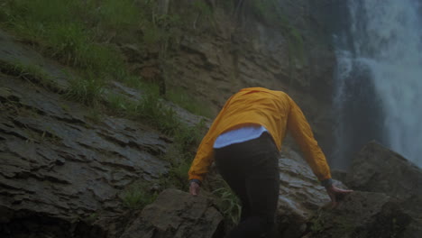 Caucasian-male-hiker-climbing-up-to-view-a-large-waterfall