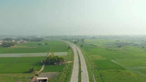 Amazing-aerial-view-of-the-well-organized-agricultural-land-divided-by-the-express-highway-in-Punjab-province,-INDIA