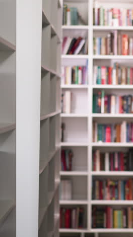 empty aisle between high bookshelves in library. shelving units with different books in contemporary public literature storage. education and knowledge